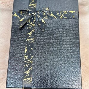 Caja de regalo con textura de piel de cocodrilo y lazo negro con detalles dorados